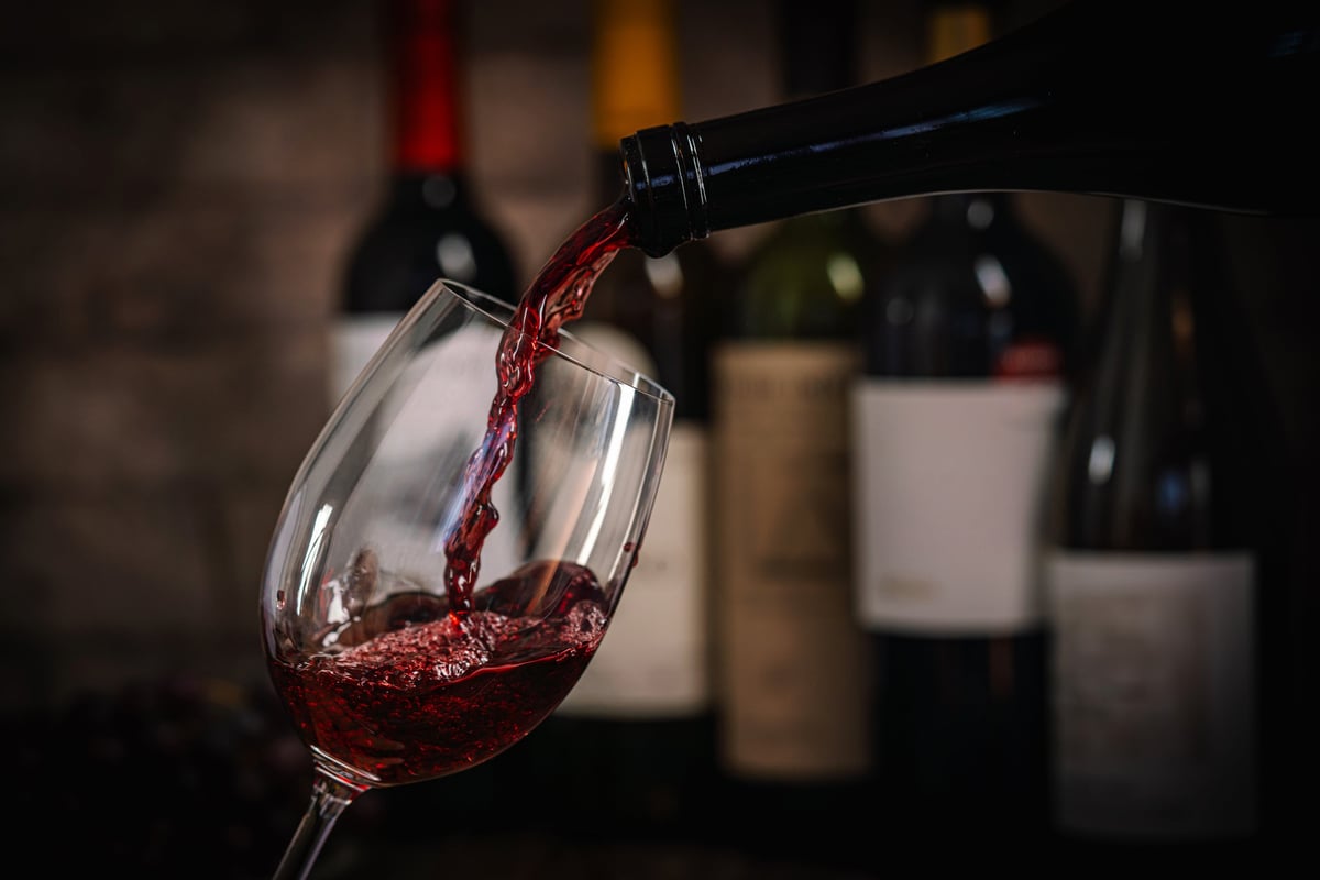 Red wine being poured into a glass, dark and elegant