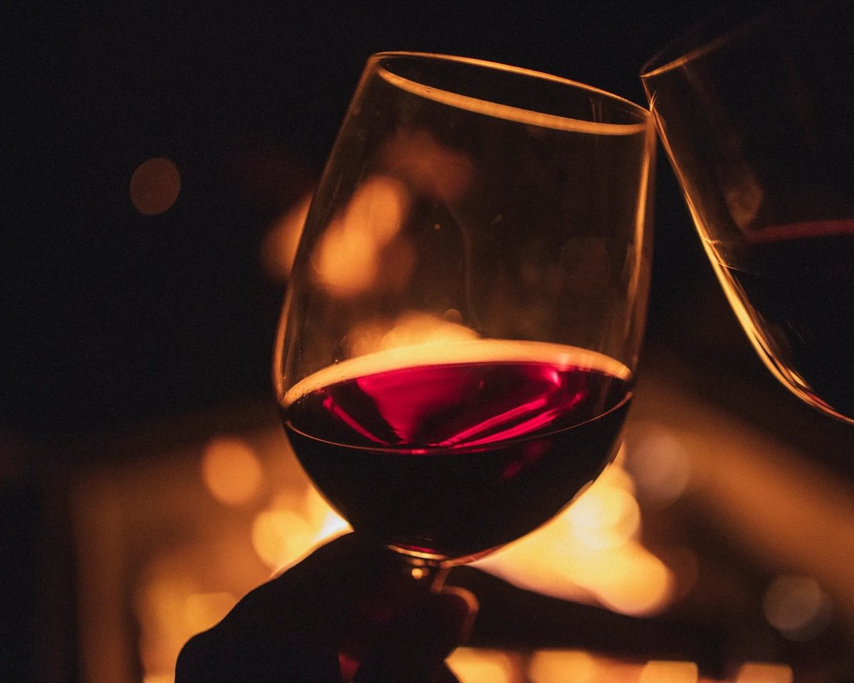 Glass of red wine illuminated against warm golden bokeh lights in the DOMUS dining room